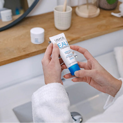 Hands holding a tube of Uriage Eau Thermale cream.