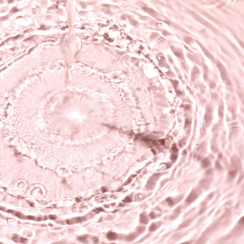 Water pouring into a pink liquid, creating concentric ripples.