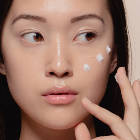 Woman applying cream to her face.