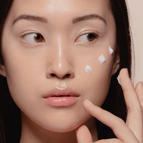 Woman applying cream to her face.