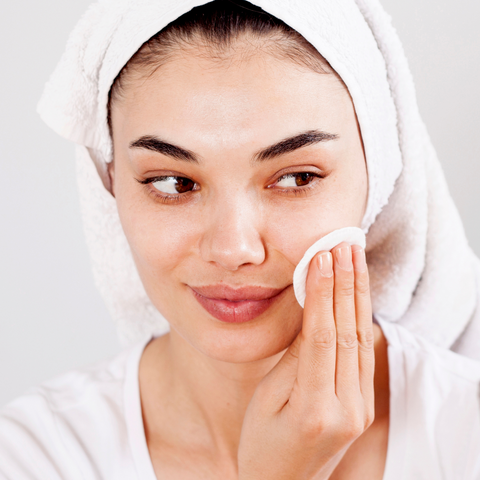 Woman cleaning face with cotton pad