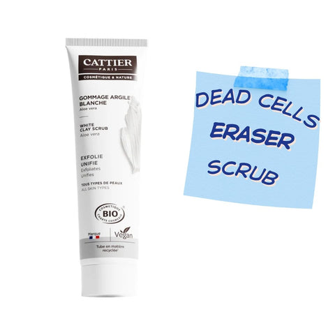 A tube of Cattier Paris Gommage Argile Blanche White Clay Scrub stands next to a light blue sticky note with the handwritten text 'DEAD CELLS ERASER SCRUB' on a plain white background.