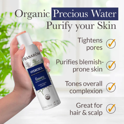 Hand holding a Pranarom organic precious water spray with text highlighting benefits on a blurred green background